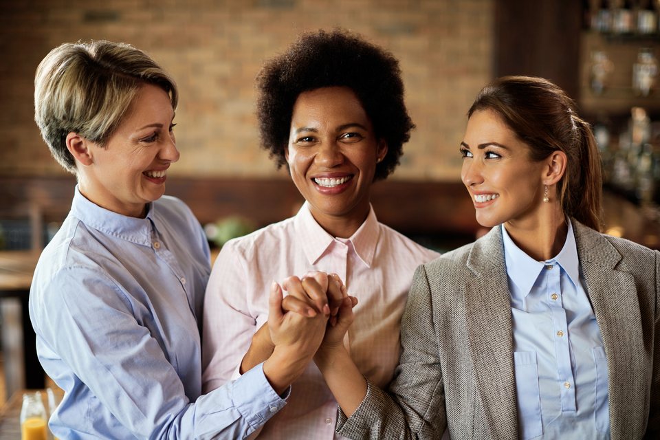 Three happy businesswomen supporting each other